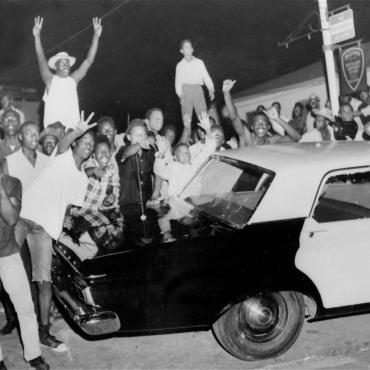 Protesters push against a police car on Aug. 12, 1965, after rioting erupted in the Watts neighborhood of Los Angeles, Calif.